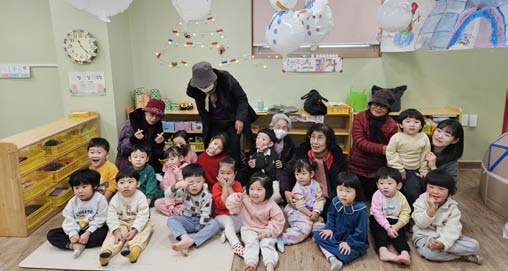 어르신들이 만든 치매인식 컬러링북을 받은 어린이집 아이들이 함께 모여 있는 모습